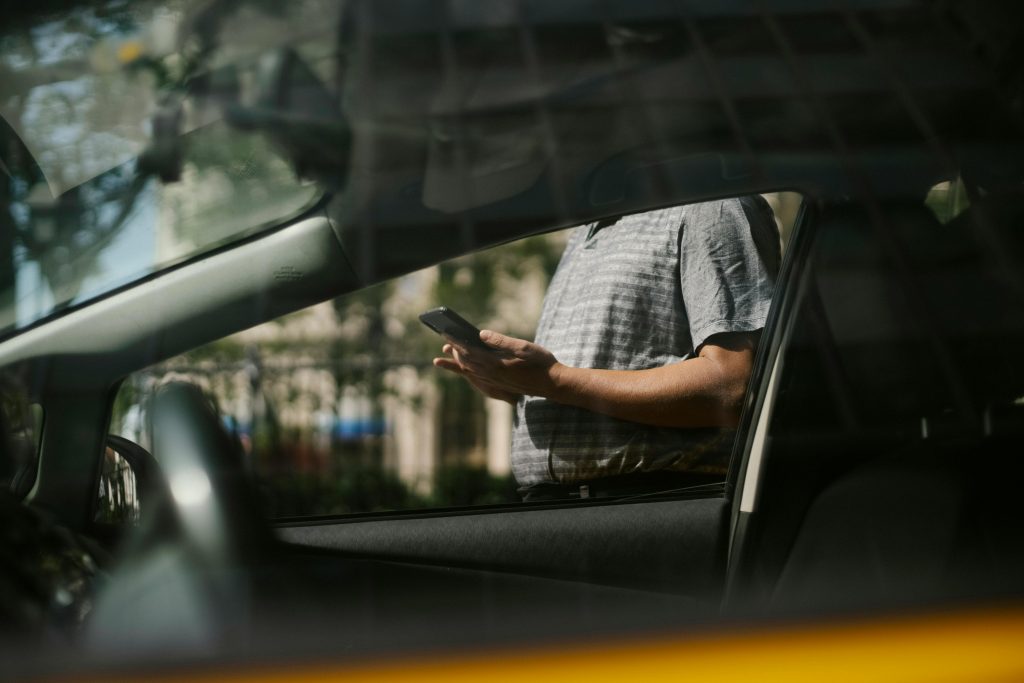 Person tippt Telefonnummer ins Handy außerhalb des Autos